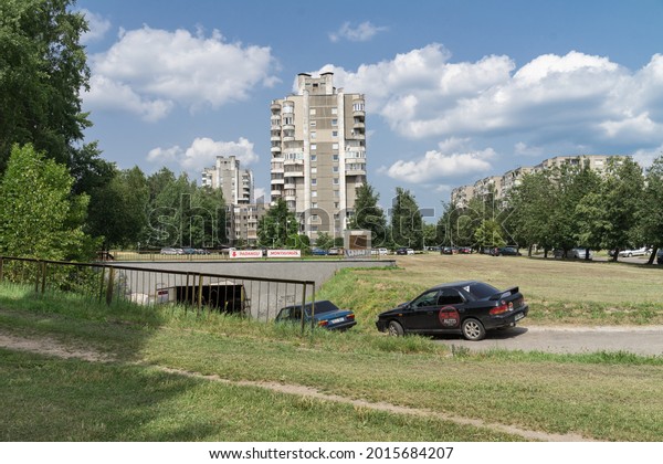 Vilnius Lithuania - July 16 2021: Soviet time\
apartement houses near Virsuliskes Forest Park on Laisves street.\
Tall building surrounded by cars of residents. Car repair in\
underground in front.