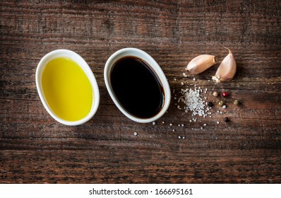 Vinaigrette Or French Dressing Recipe Ingredients On Vintage Wood Background. Olive Oil, Balsamic Vinegar, Garlic, Salt And Pepper From Above.