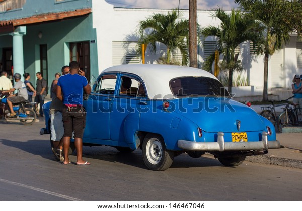 VINALES -\
FEBRUARY 4: Two men talk with the driver of classic car parked on\
the street on February 4, 2013 in Vinales. These old and classic\
cars are an iconic sight of the Cuba island\
