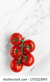 Vine of Ripe Red Tomatoes on the Bottom on a White Marble Background with Space for Copy