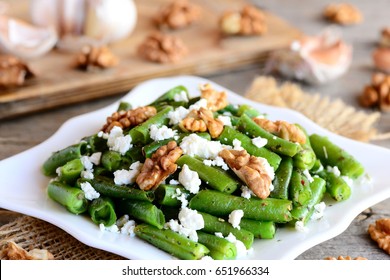 Vinegar And Oil Green Bean Salad Recipe. Delicious Green String Beans Salad With Cottage Cheese, Peeled Walnuts, Garlic And Spices On A White Plate And Wooden Table. Warm Salad For Healthy Dinner Idea