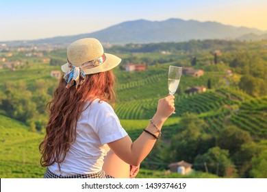 Vineyard Prosecco on the green hills near Valdobbiadene, girl with a glass of Prosecco wine, Veneto, Italy