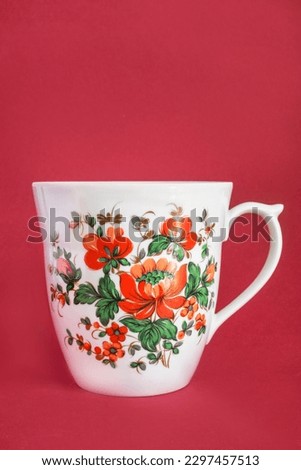 Vingage ceramic painted cup on red studio background