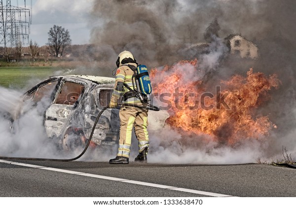 Vinkeveen, Utrecht, Netherlands - March 8th\
2019: Fire brigade at work, extinguishing car, along the A2 highway\
at Vinkeveen\
