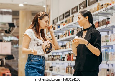 VINNITSA, UKRAINE - September 10, 2019: Young pretty woman chosing perfume and beauty consultant in market or beauty salon