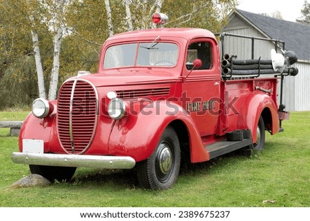 Vintage 1935 red fire truck with hose, axe, and two fireman helmets. This restored fire truck was once used by the fire department in Sugar Hill, New Hampshire.