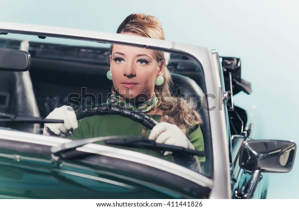 Vintage 1960s\
woman driving a convertible\
car.