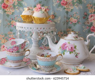 Vintage Afternoon Tea Party - Blue Floral Tea Cup And Saucer, Pink Roses Teapot And White Cake Stand With Cupcakes On A Floral Table Cloth