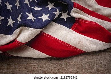 Vintage American flag draped across a rustic wooden background - Powered by Shutterstock