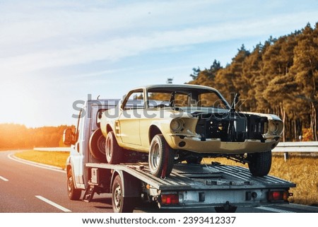 Vintage american muscle car body is on the flatbed towtruck after body works. Painting body of the car. Recover a Retro Car After an Accident. A Project to Restore a Classic Car with the Help of a Tow