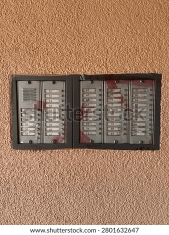 Vintage analog intercom system panel with apartment numbers on a textured wall