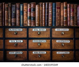 Vintage, Antiquarian Books On Wooden Old Pharmaceutical Cabinet. Translation From Latin Language Names Of Medicines Funds: Horsetail, Hemp, Mallow Leaves, Diuretic, Parsley, St. John's Wort, Trefoil.