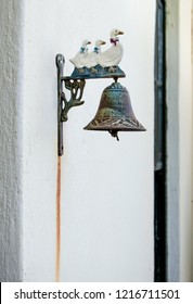 A vintage / antique door bell design mounted on the wall of a traditional old farm house. It is styled with a row of ducks and has started to rust.