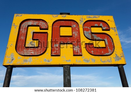 A vintage, antique, gasoline sign in front of a blue sky on  a sunny day