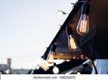 Vintage antique hanging light bulbs at a street food market. Holidays and business good idea concept.