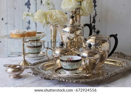 Vintage antique silver tea and coffee set on tray with milk jug, sugar bowl, teacup and saucer, vase of roses and tea strainer - high tea party