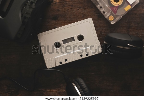 Vintage audio cassette between headphones\
and personal cassette player on a wood\
surface