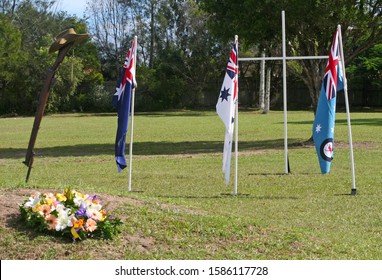 Vintage Australian Army 303 rifle, a soldier's dogtags, iconic Aussie slouch hat (clearly showing the rising sun badge) and a floral wreath with Australian National Flag in background on ANZAC Day.