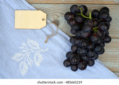 Vintage Background With A Bunch Of Fresh Organic Purple,black Grapes On A Empty Copy Space Background With A Blank Label Tag And Tea Towel..