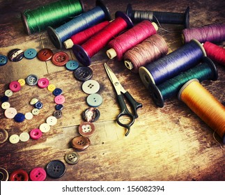 Vintage Background with sewing/Sewing kit. Scissors, bobbins with thread and needles on the old wooden background - Powered by Shutterstock