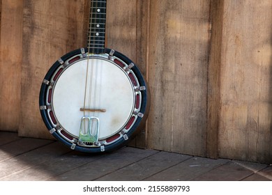 Vintage Banjo-mandolin, close up of body, in sunlight on a wooden deck porch.