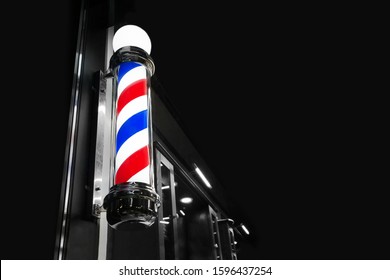 vintage Barbershop window pole on the black background with space for text. Old-fashioned barber pole in the window, night shot, selective focus.