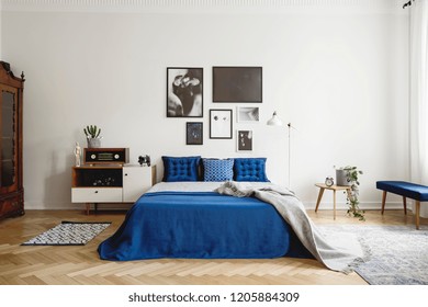 Vintage Bedroom Interior With Bedside Table, King Size Bed With Blue Bedding And Pillows. Mockup Gallery On The White Wall. Real Photo Concept