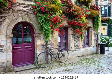 Vintage bicycle in front of the old rustic house, covered with flowers. Beautiful city landscape with an old bike near the stone wall with flowers in drawers in France, Europe. Retro style. - Powered by Shutterstock