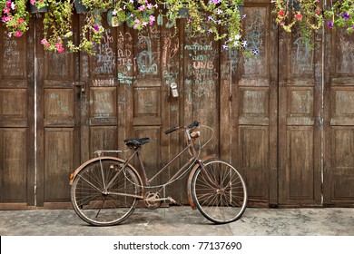 Vintage bicycle in front of old rustic house, covering with the flower on roof and many text on the wall. Classic bike Vintage bicycle and old house decorated perfectly look like retro style.  - Powered by Shutterstock