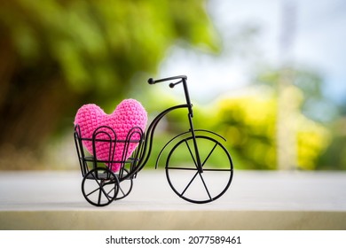 Vintage Bicycle Model With Transport A Pink Heart On Sunlight In The Public Park For Supporting When People Get Who Lack Of Desire With Love And Valentine's Day Concept.