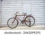 Vintage bicycle on old rustic dirty wall house, many stain on wood wall. Classic bike old bicycle on decay brick wall retro style. Cement loft partition and window background.