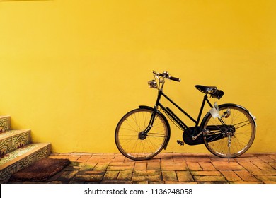 A Vintage Bicycle Park In Front Of The Yellow Fresco Painting Wall