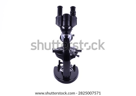 Vintage binocular microscope viewed from the rear, showing dual eyepieces, optical head, mechanical stage, focusing controls and sturdy laboratory base isolated on a white background.