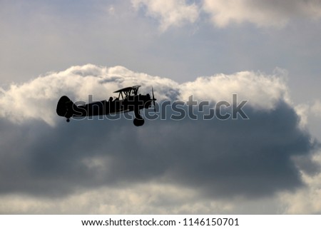 Vintage biplane silhouetted against an evening sky