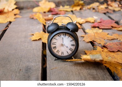 Vintage Black Alarm Clock On Autumn Leaves. Time Change Abstract Photo. Daylight Saving Time.
