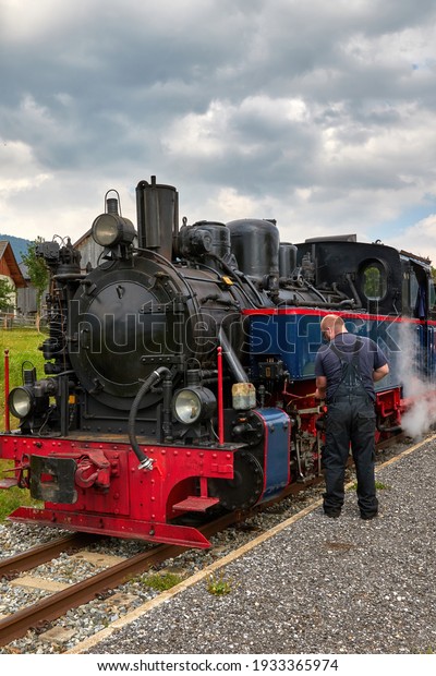 Vintage black steam locomotive train. Steam\
train. Man maintaining the\
locomotive
