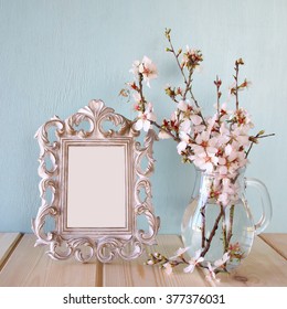 vintage blank frame next to white spring flowers. selective focus. template, ready to put photography
