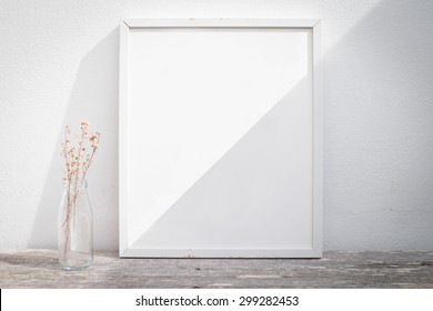 Vintage blank picture frame and sunlight on a wall.