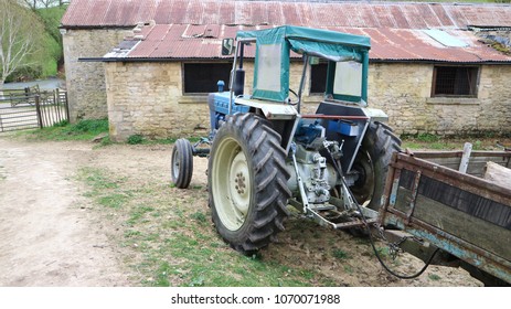 Vintage Blue Tractor With Trailer On Farm Yard