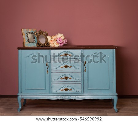 Vintage blue wooden dresser, tender bouquet and two frames. Blue and brown vintage interior. Brown room with ethnic dresser. Antique cupboard. Clothes closet. Vanity Table
