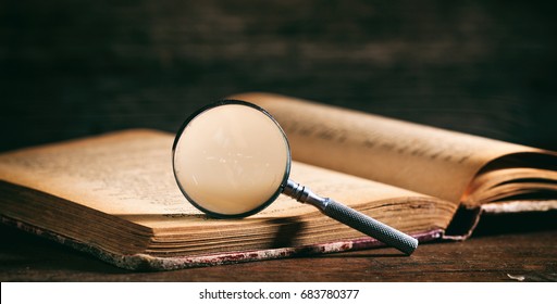 Vintage book and magnifying glass on wooden background
 - Powered by Shutterstock