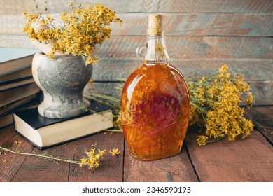 Vintage books, dried St. John's wort flowers and bottles of St. John's wort oil on a wooden background.