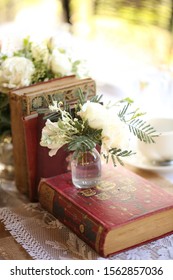 Vintage Books With Vases Of White Roses On Lace Table Runner