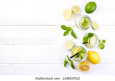 Vintage Bottle With Two Glasses Of Refreshing Non Alcoholic Mojito Lemonade, Sparkling Water Drink With Lemon, Lime Slices, Mint Leaves, Straw, Wooden Table Background. Close Up, Top View, Copy Space.