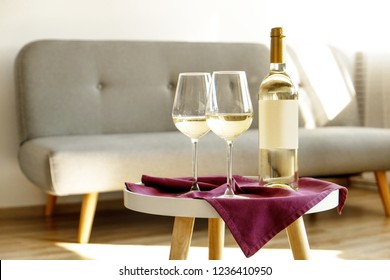 Vintage Bottle Of White Wine With Blank Matte Label And Two Glasses On Purple Napkin, Lofty Interior Background. Expensive Bottle Of Shardonnay Concept. Copy Space, Top View, Flat Lay, Close Up.