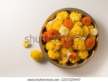 A vintage brass bowl filled with fresh, golden colored Marigold flowers. Top view of Marigold flowers for Indian festive occasions.