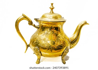 Vintage Brass Teapot decorated with a handcrafted design in relief with tree leaves shape. Reflective shining surface golden colored metal alloy. Studio shot isolated in white background. 