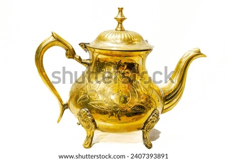 Vintage Brass Teapot decorated with a handcrafted design in relief with tree leaves shape. Reflective shining surface golden colored metal alloy. Studio shot isolated in white background. 