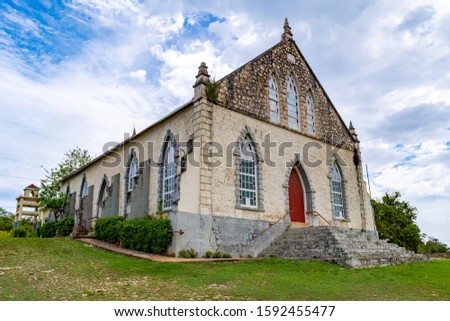Vintage brick/ concrete wall chapel with red front door and stained glass windows in the countryside. Duncans Methodist Church in Trelawny parish, Jamaica, built in AD 1882.