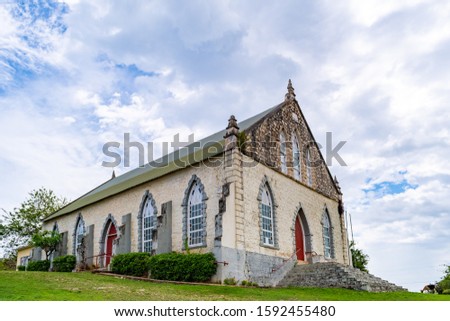 Vintage brick/ concrete wall chapel with red front door and stained glass windows in the countryside. Duncans Methodist Church in Trelawny parish, Jamaica, built in AD 1882.